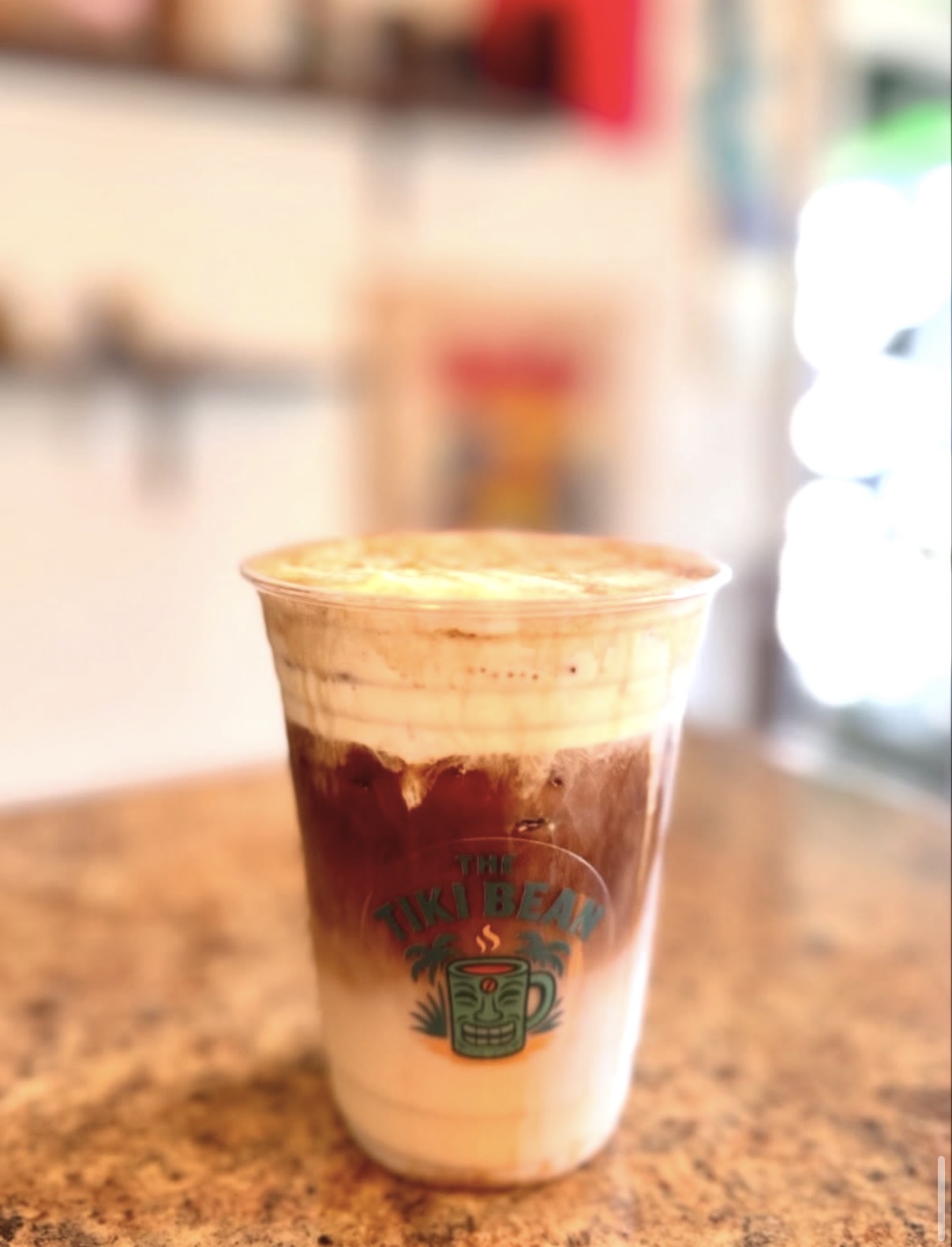 A layered iced Tiki Bean coffee in a branded cup