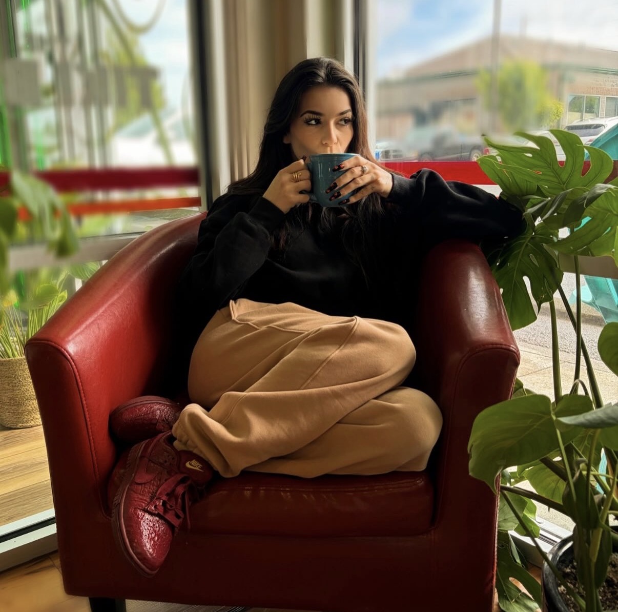 A guest relaxing in a red leather chair with a teal mug by the window